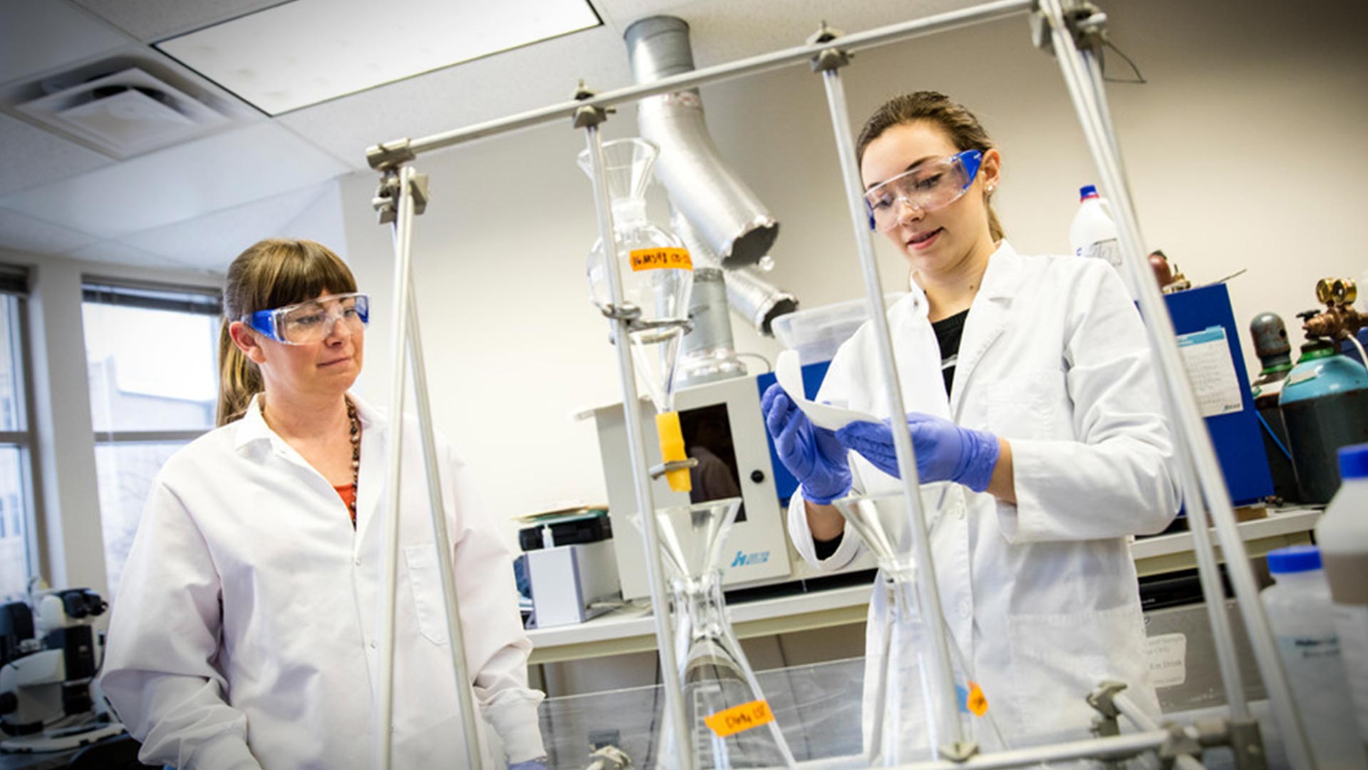 Students with protective eye gear conducting research in a lab.